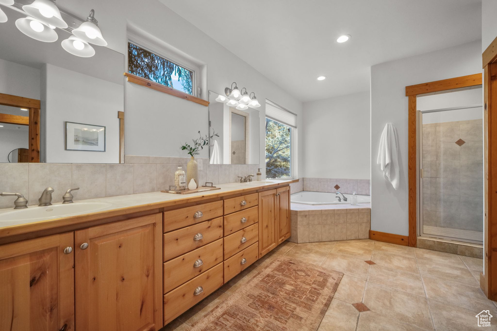 Bathroom featuring vanity, backsplash, tile patterned floors, and plus walk in shower