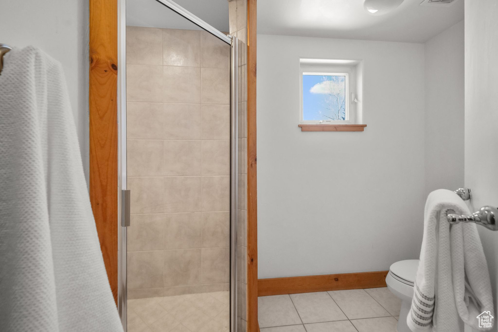 Bathroom with toilet, a shower with curtain, and tile patterned floors