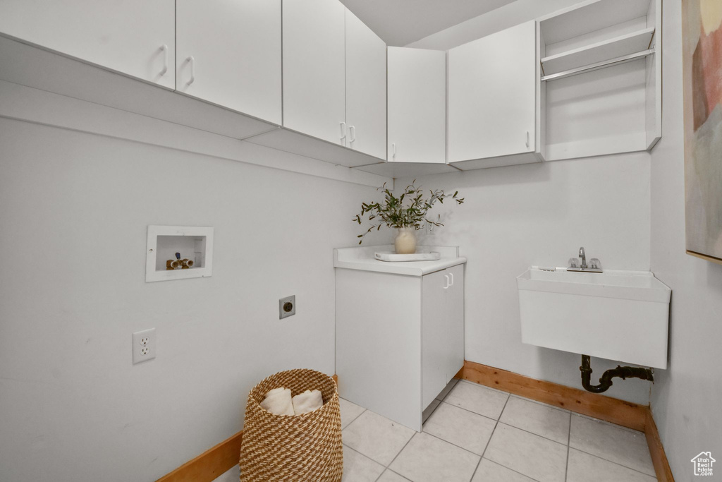 Clothes washing area featuring sink, hookup for a washing machine, light tile patterned floors, hookup for an electric dryer, and cabinets