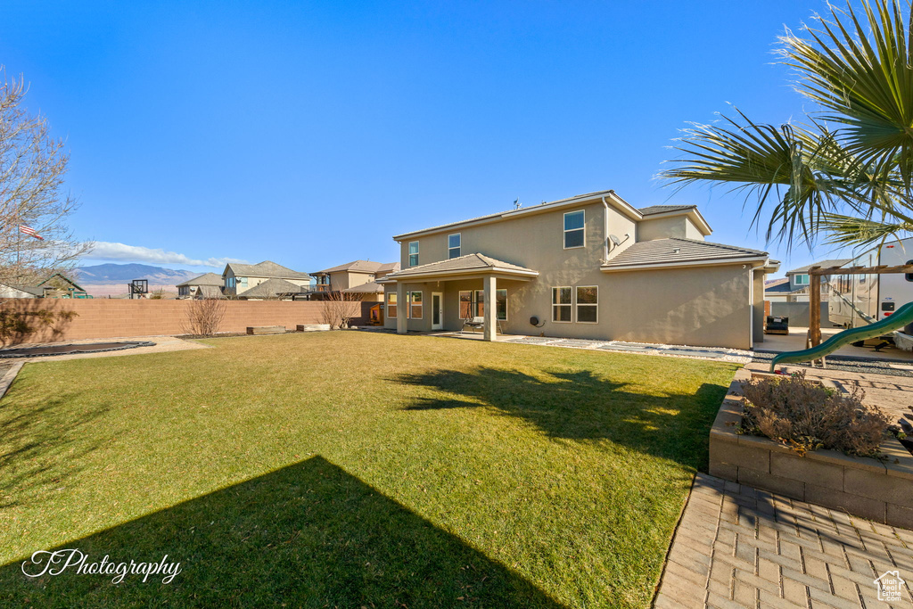 Back of house featuring a mountain view, a yard, and a playground