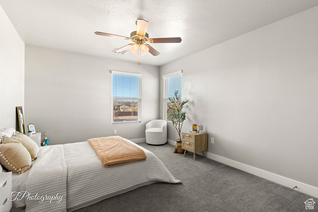 Carpeted bedroom featuring ceiling fan and a textured ceiling