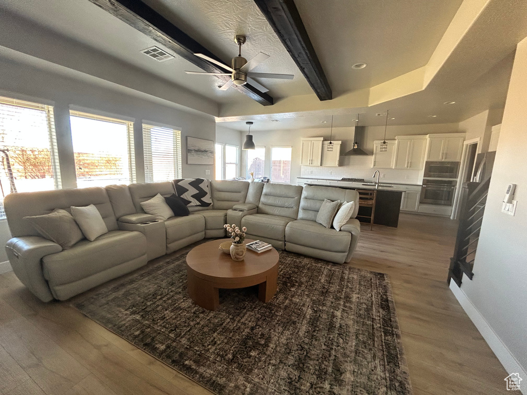 Living room with sink, light hardwood / wood-style flooring, beamed ceiling, and ceiling fan