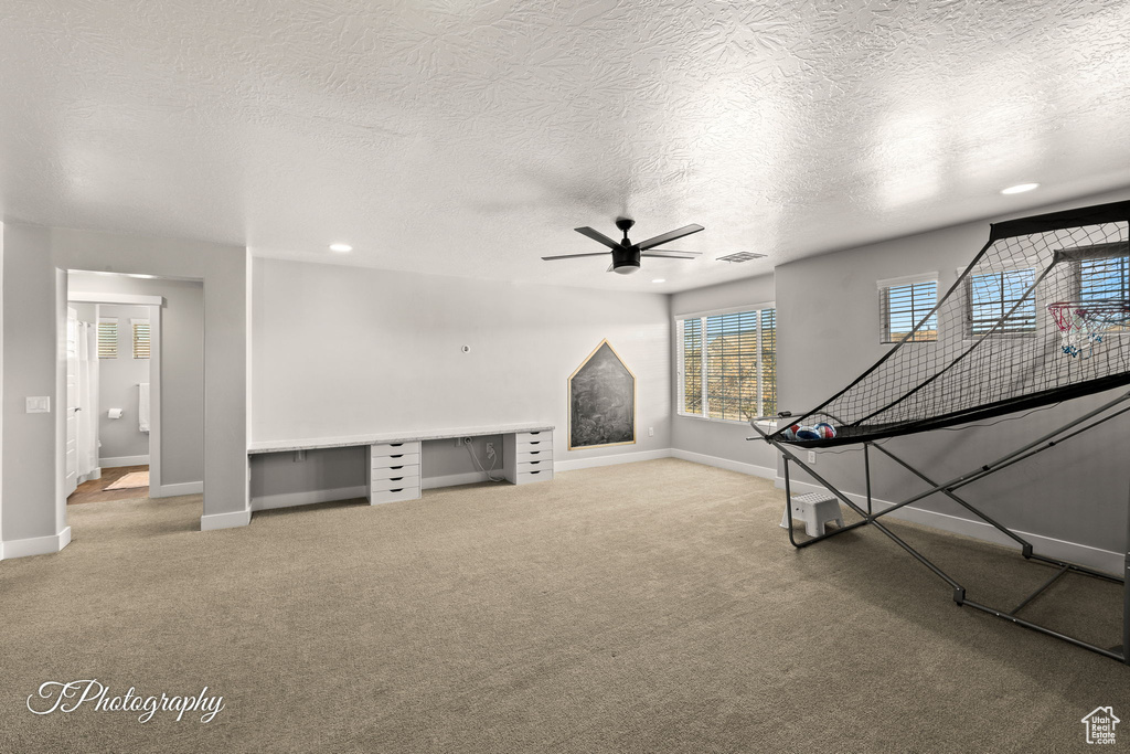 Interior space with ceiling fan, carpet, and a textured ceiling