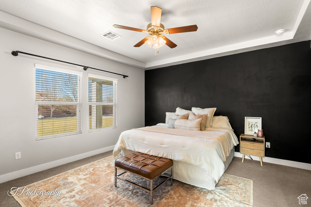 Carpeted bedroom featuring a textured ceiling and ceiling fan