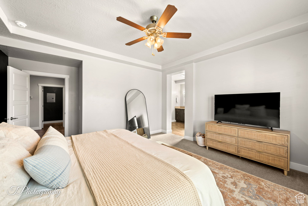 Carpeted bedroom featuring ceiling fan, ensuite bathroom, and a textured ceiling