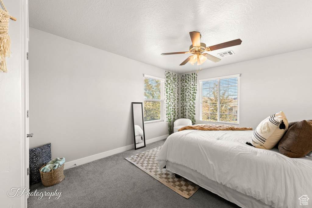 Bedroom with ceiling fan, carpet, and a textured ceiling