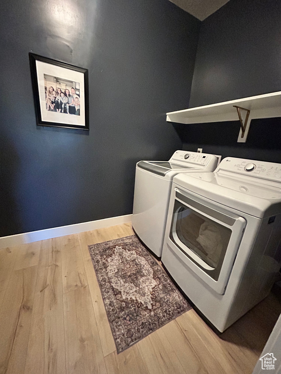 Laundry room with hardwood / wood-style flooring and washing machine and clothes dryer