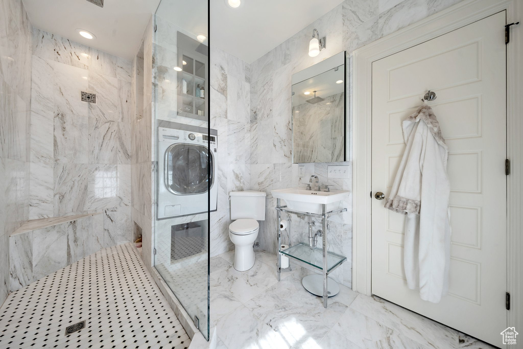 Bathroom with washer / clothes dryer, a shower, tile walls, and toilet