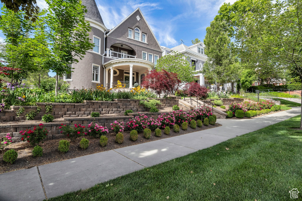 View of front of home featuring covered porch, a balcony, and a front lawn