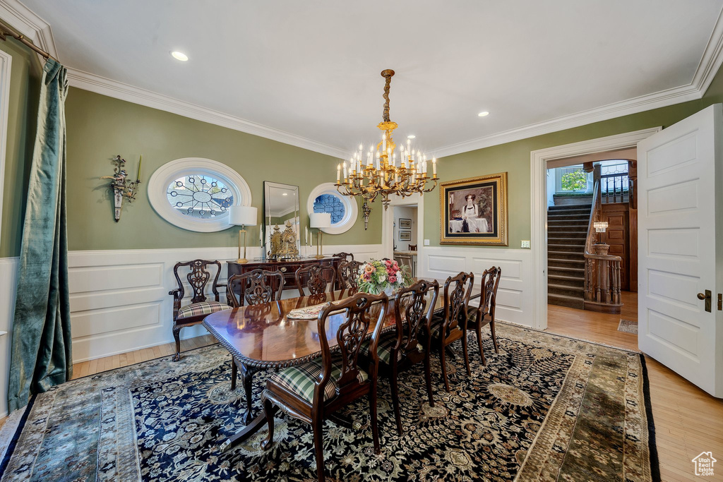 Dining space featuring light hardwood / wood-style floors, an inviting chandelier, and ornamental molding