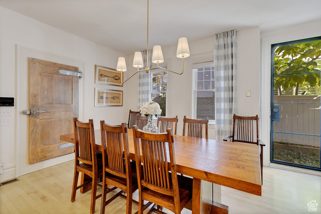 Dining room with light hardwood / wood-style floors and a notable chandelier