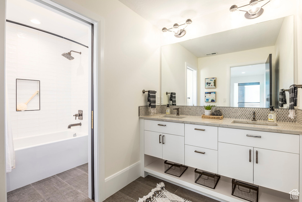 Bathroom with decorative backsplash, shower / washtub combination, and vanity