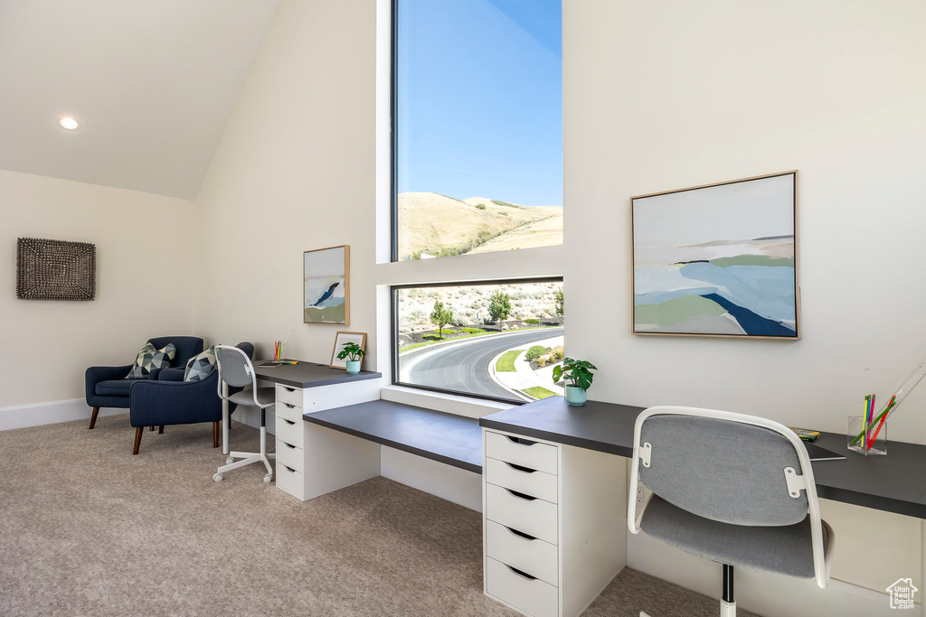 Home office with a mountain view, a healthy amount of sunlight, light carpet, and high vaulted ceiling