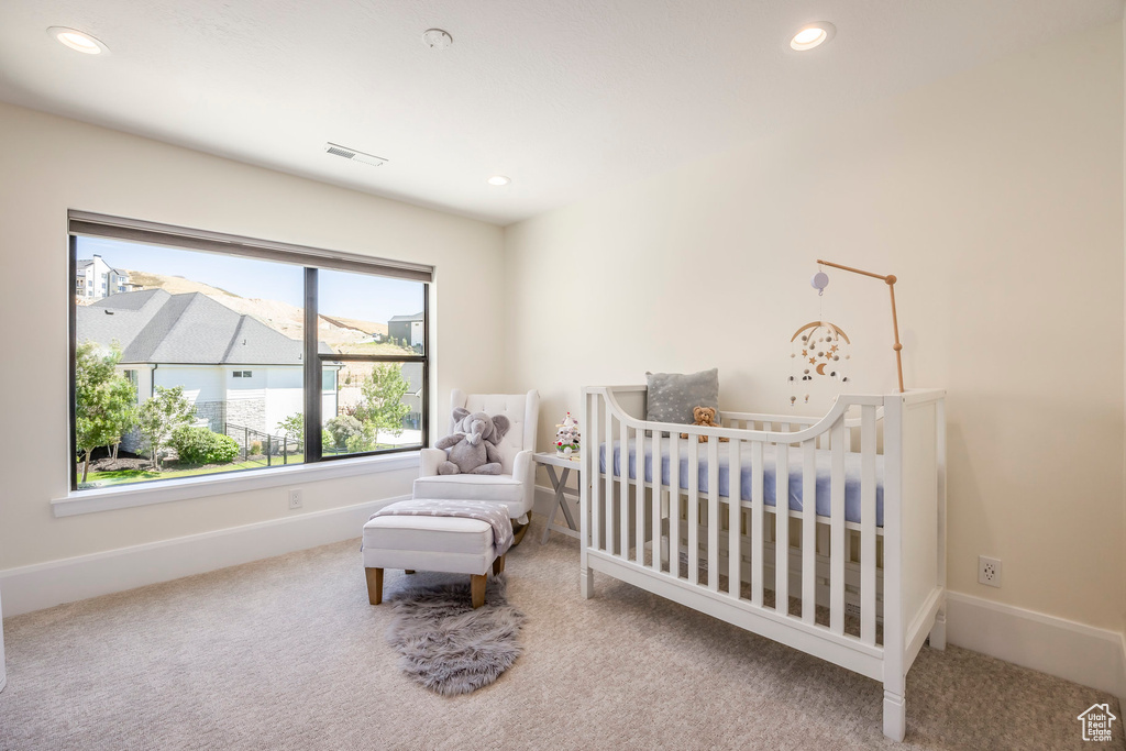 Bedroom with a crib and carpet flooring