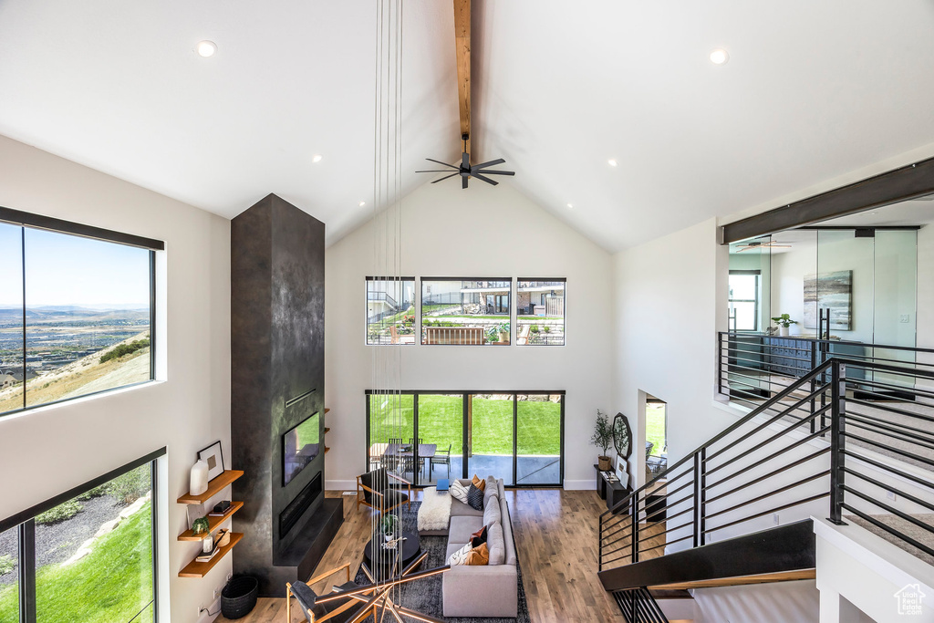Living room with beam ceiling, wood-type flooring, a fireplace, and high vaulted ceiling