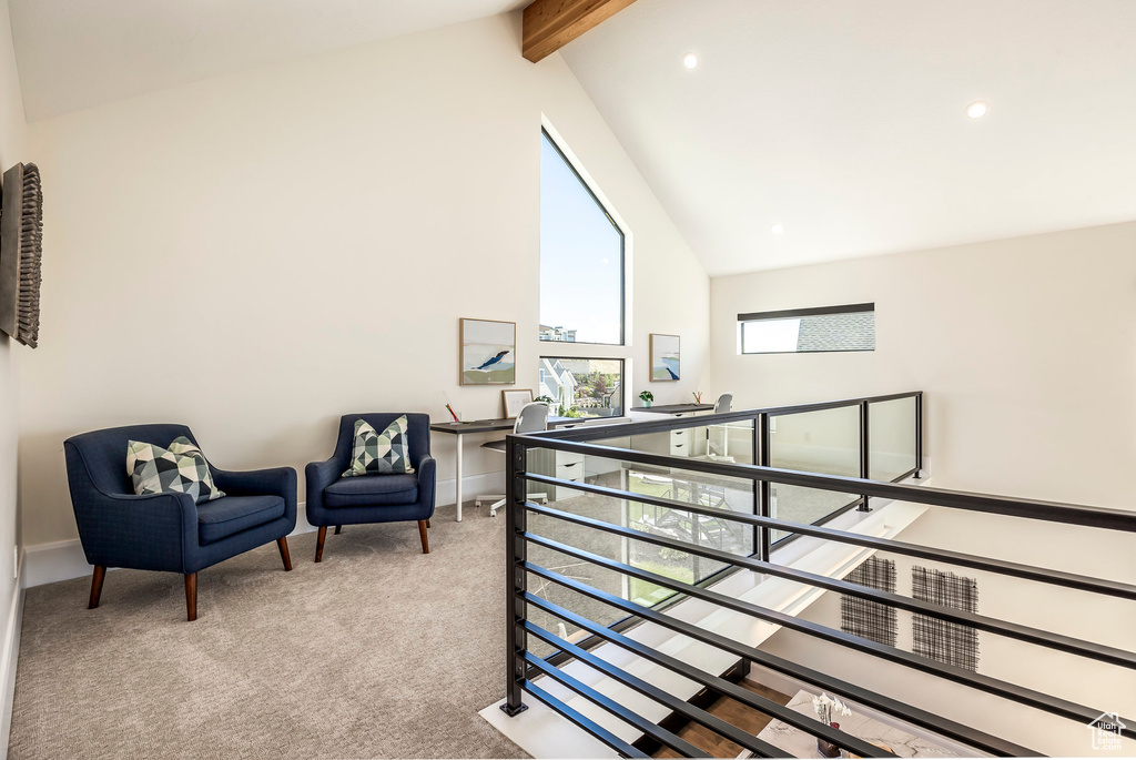 Sitting room with beamed ceiling, light colored carpet, and high vaulted ceiling