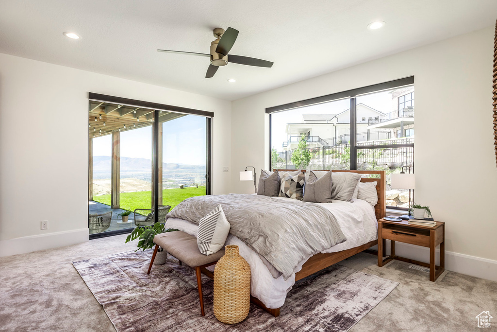 Bedroom with a mountain view, access to outside, ceiling fan, and light colored carpet