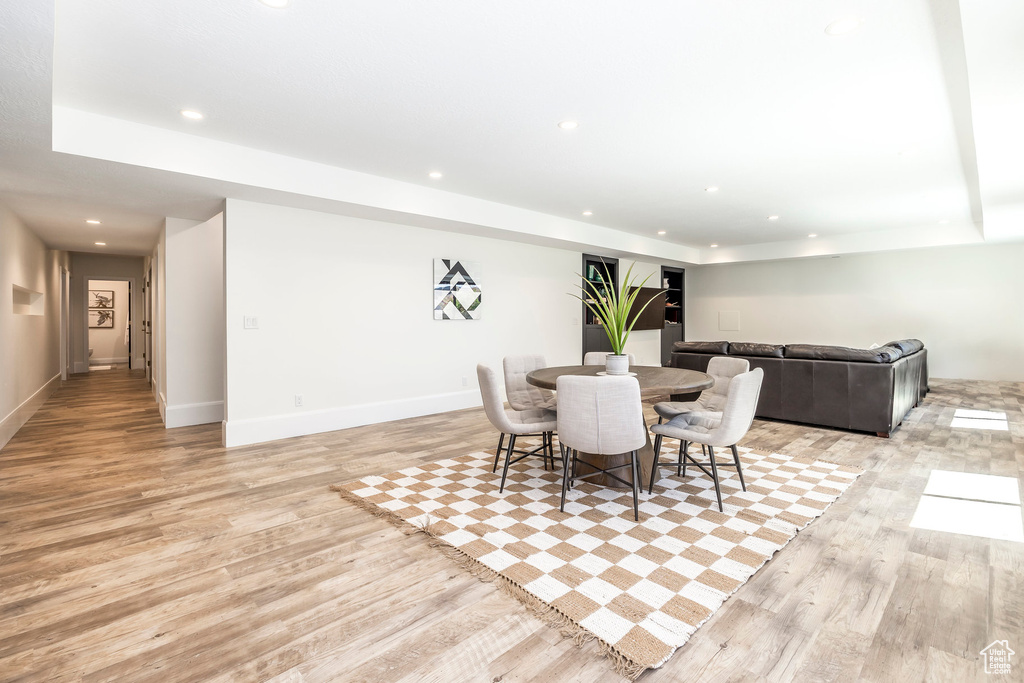 Dining area with light hardwood / wood-style floors and a raised ceiling