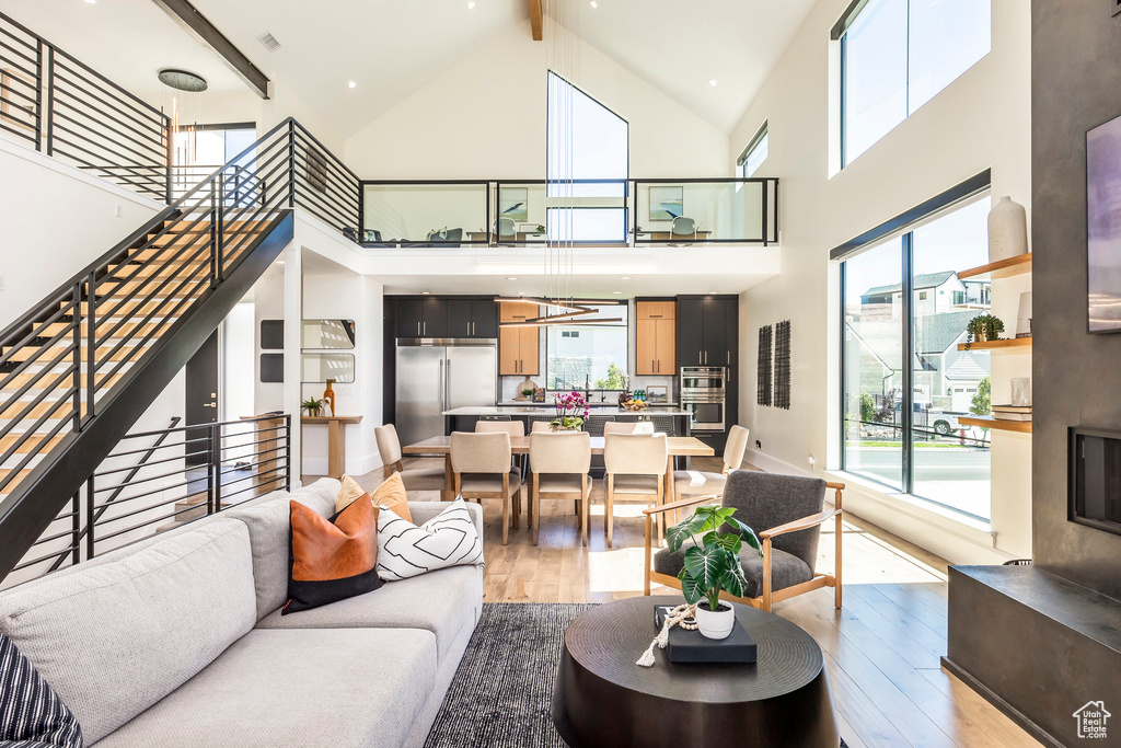 Living room with beam ceiling, light hardwood / wood-style floors, and high vaulted ceiling