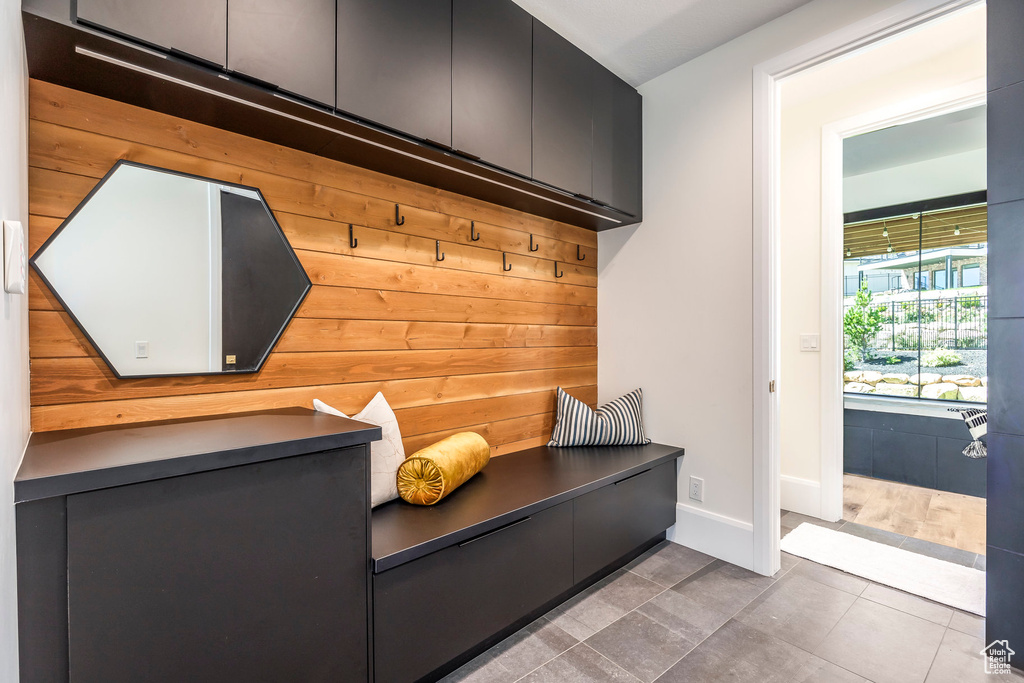 Mudroom with tile patterned floors and wood walls