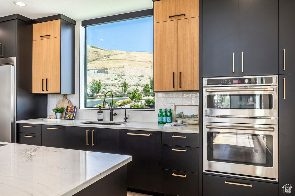 Kitchen with light stone countertops, appliances with stainless steel finishes, tasteful backsplash, sink, and a mountain view