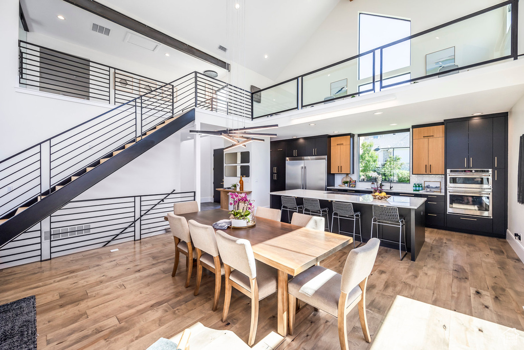 Dining space with a towering ceiling and light hardwood / wood-style flooring