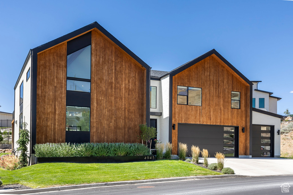 Contemporary house featuring a front yard and a garage