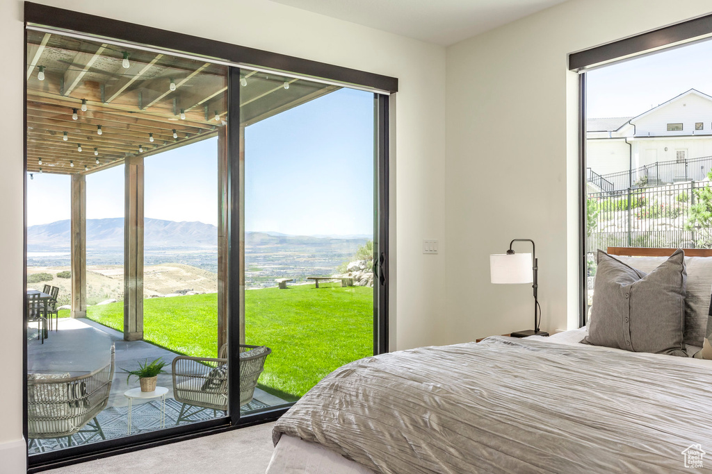 Carpeted bedroom with access to exterior, a mountain view, and multiple windows