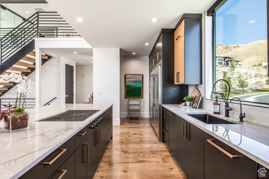 Kitchen featuring a mountain view, sink, light hardwood / wood-style flooring, light stone counters, and stainless steel appliances