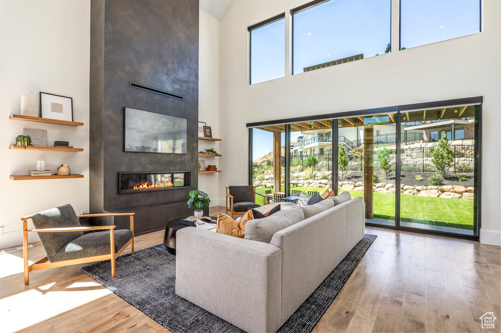 Living room with hardwood / wood-style floors, a large fireplace, and a towering ceiling