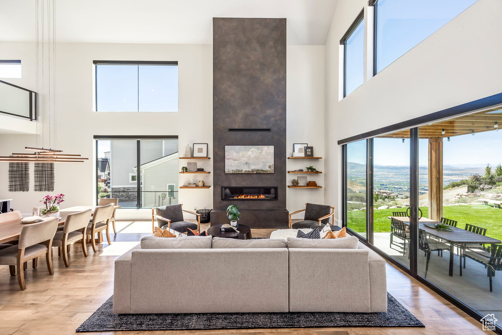Living room with a large fireplace, a towering ceiling, and light hardwood / wood-style flooring