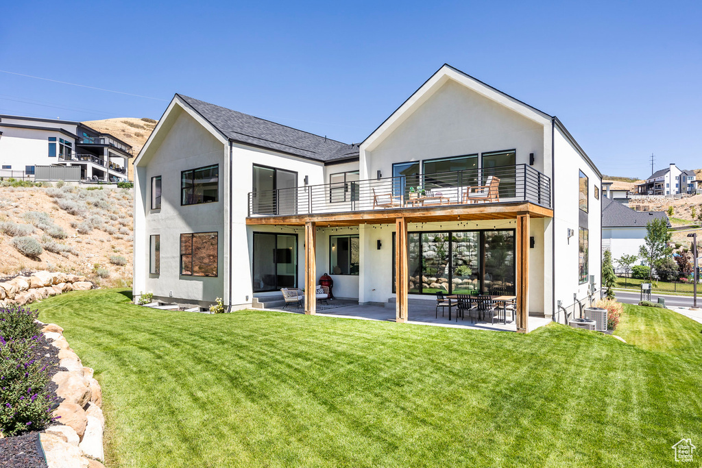 Back of property with a yard, a balcony, a patio area, and central air condition unit