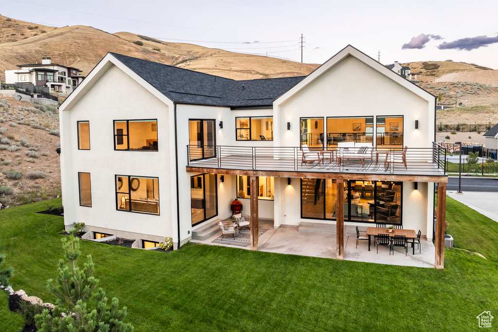 Back of property featuring a lawn, a mountain view, and a patio