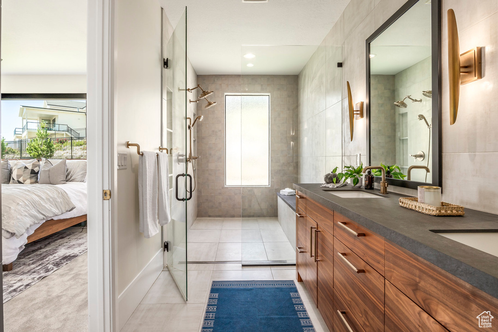 Bathroom featuring a shower with door, vanity, and tile patterned flooring