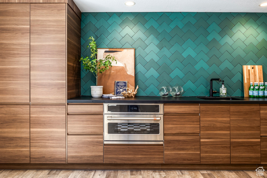 Kitchen with oven, light hardwood / wood-style floors, and sink