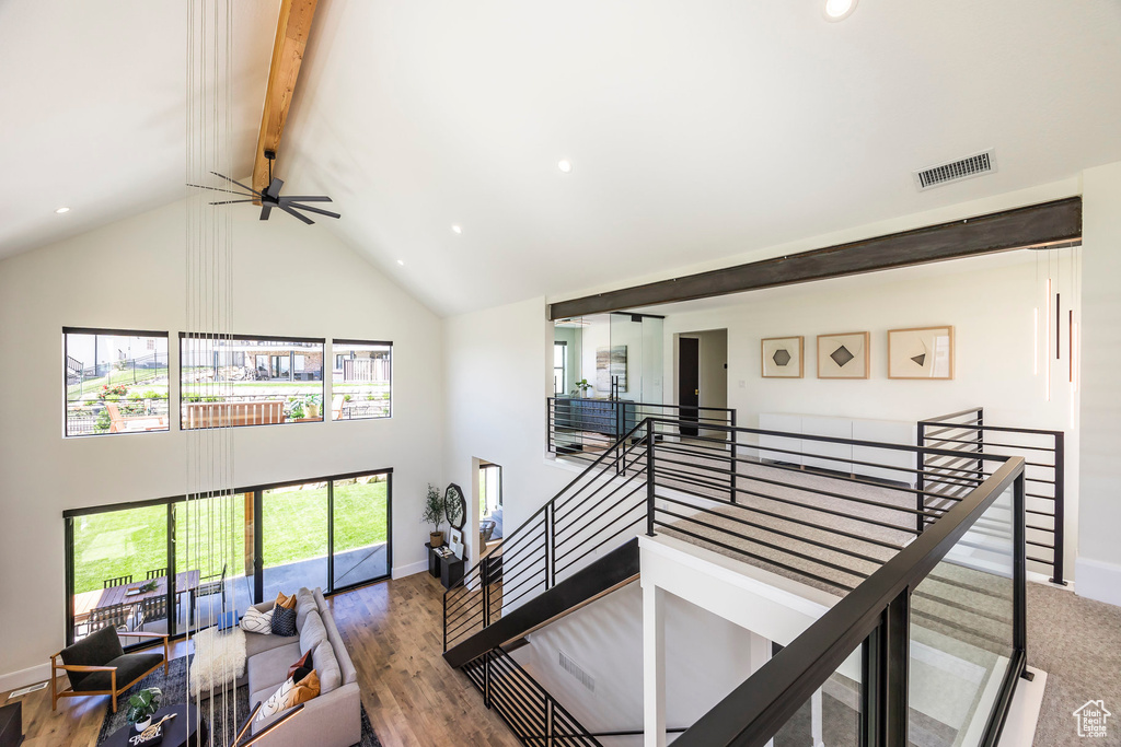Stairway featuring beam ceiling, ceiling fan, high vaulted ceiling, and wood-type flooring
