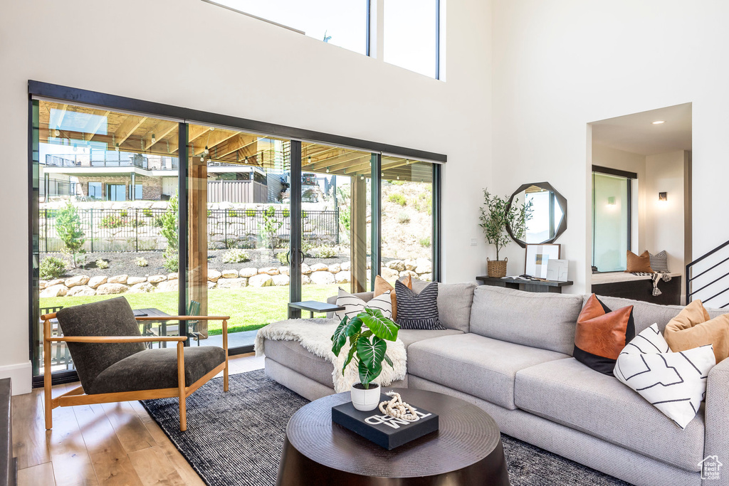 Living room with hardwood / wood-style floors, a towering ceiling, and a wealth of natural light