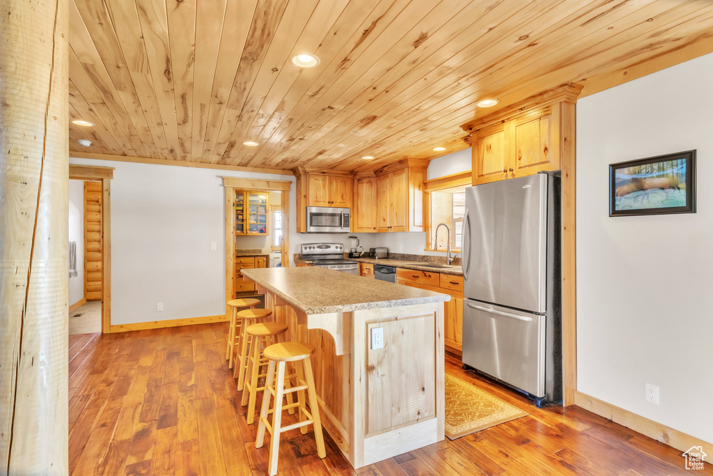 Kitchen with a kitchen bar, stainless steel appliances, sink, light hardwood / wood-style flooring, and a kitchen island