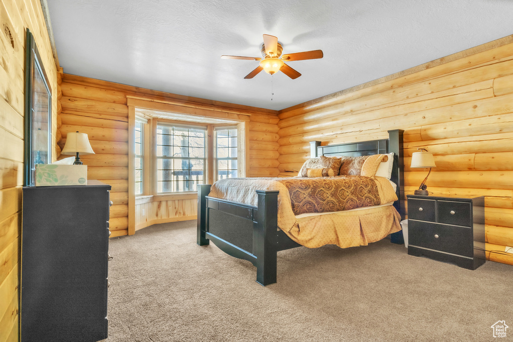 Carpeted bedroom with log walls and ceiling fan