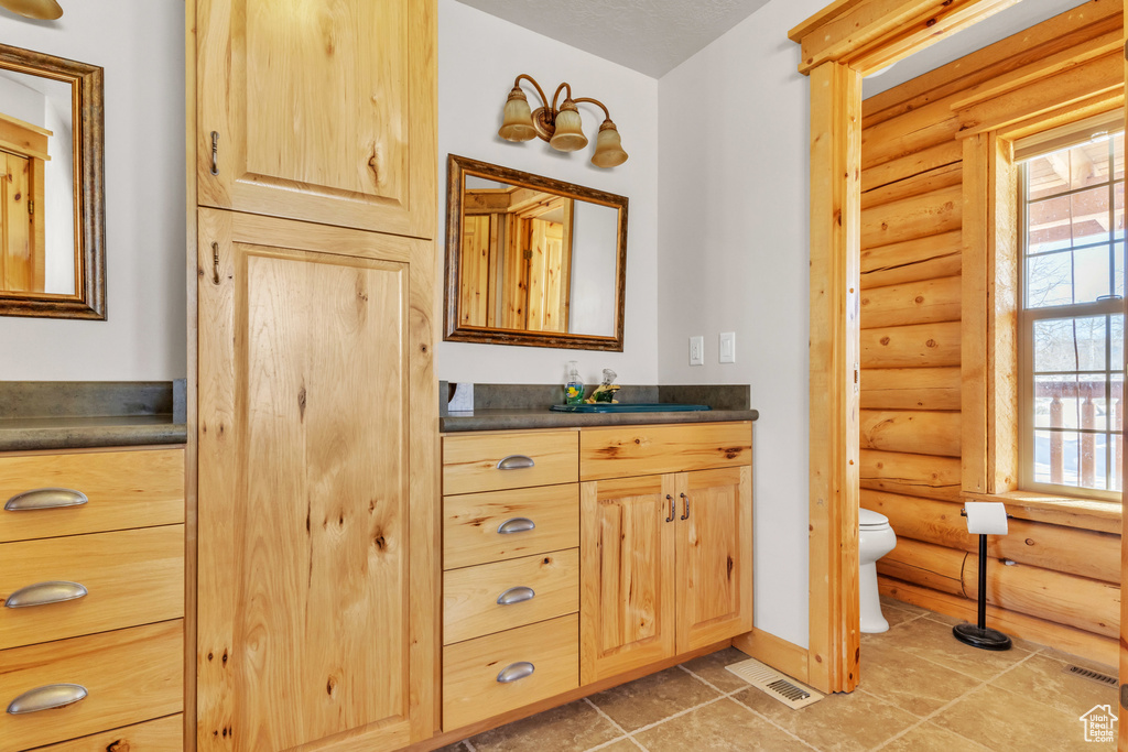 Bathroom featuring rustic walls, vanity, and toilet