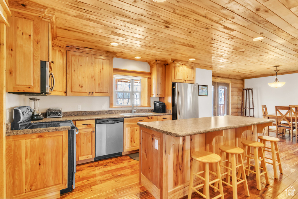 Kitchen with wooden ceiling, hanging light fixtures, sink, light hardwood / wood-style flooring, and appliances with stainless steel finishes