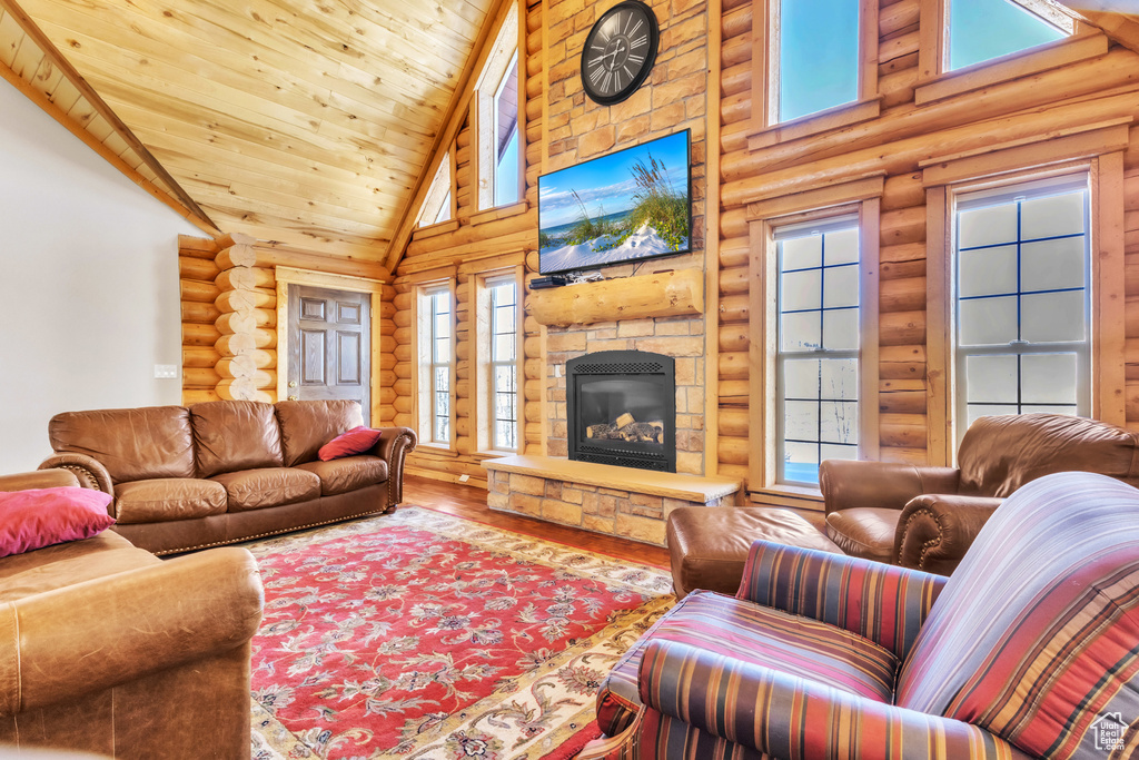 Living room with rustic walls, a stone fireplace, high vaulted ceiling, and wood ceiling