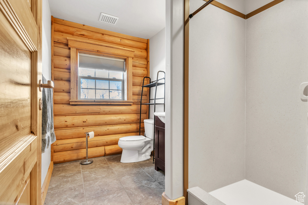 Bathroom featuring toilet, vanity, and rustic walls