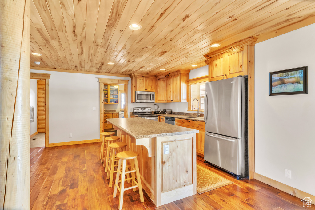 Kitchen with light wood-type flooring, a breakfast bar, stainless steel appliances, sink, and a center island