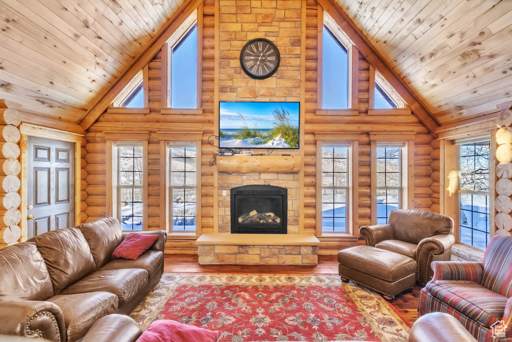 Living room with rustic walls, a fireplace, high vaulted ceiling, and hardwood / wood-style floors