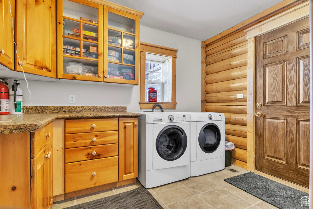Washroom with rustic walls, cabinets, and independent washer and dryer