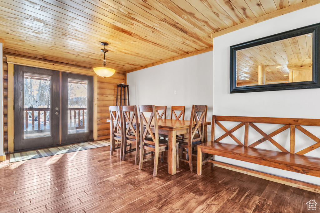 Unfurnished dining area with wood-type flooring, wood ceiling, rustic walls, and french doors