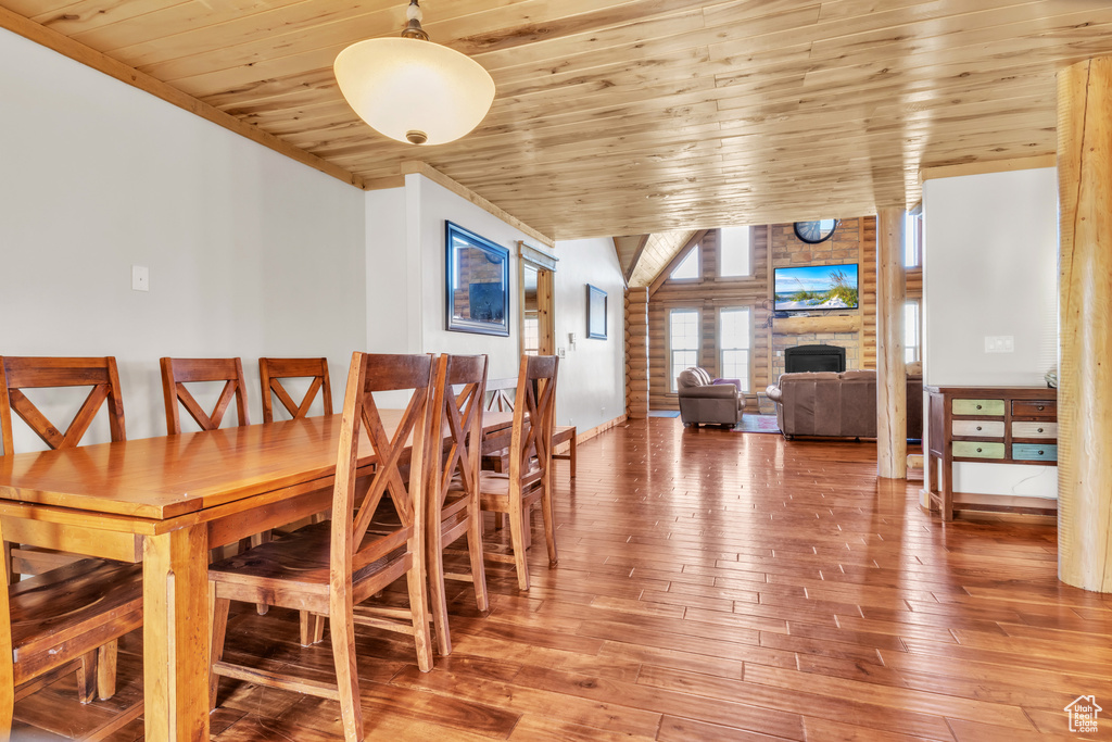 Dining area featuring hardwood / wood-style floors, lofted ceiling, wooden ceiling, and a fireplace