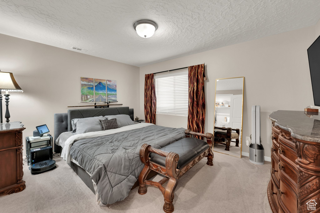 Bedroom featuring light carpet, a textured ceiling, and baseboards