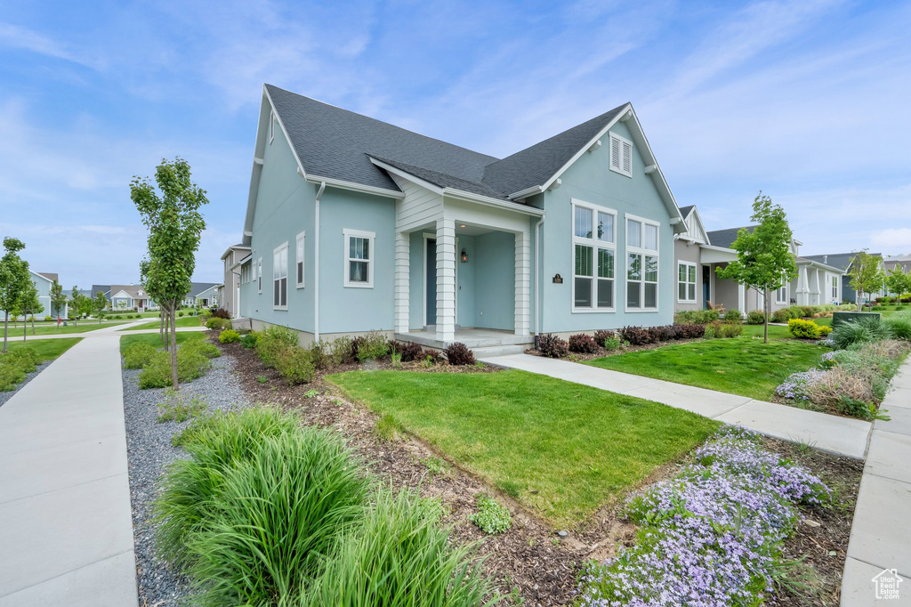View of front of property featuring roof with shingles, a front lawn, stucco siding, and a residential view